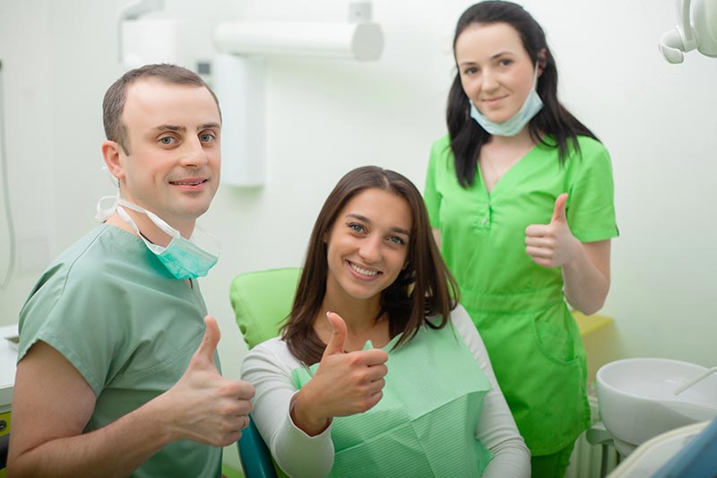 Two dentists and one patient smiling in the dental clinic